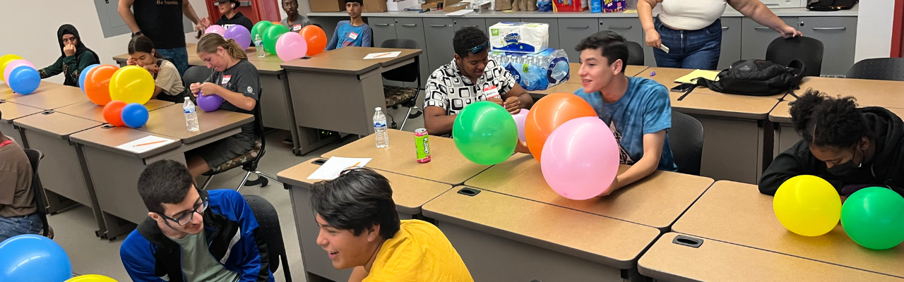 Picture of students paired up participating in an activity involving balloons.