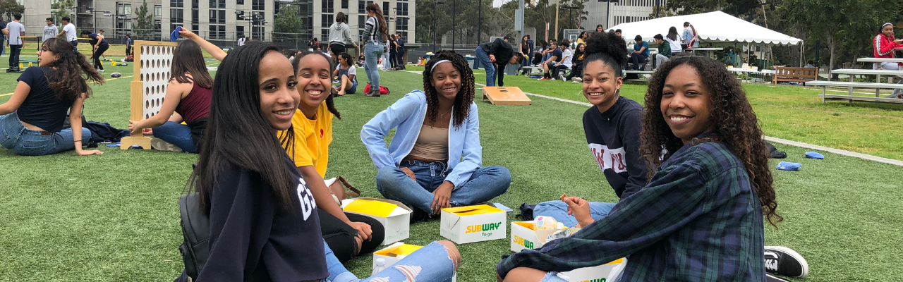 Students sitting in a circle smiling for the camera.